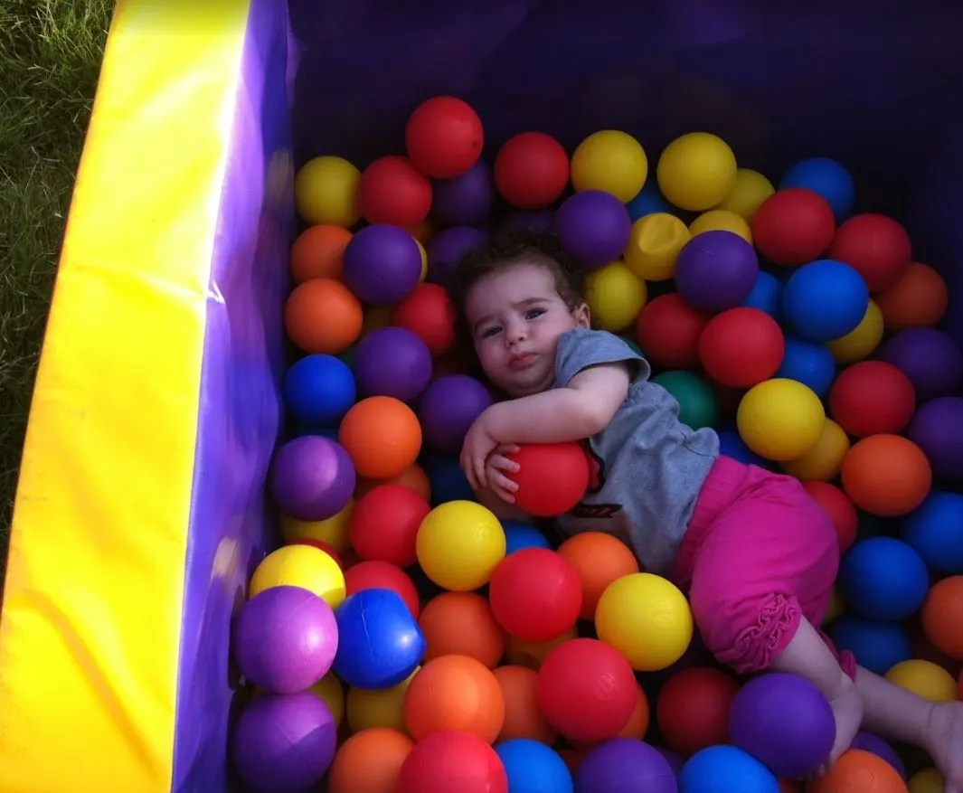 השכרת בריכת כדורים – פעוטה משחקת בבריכת כדורים צבעונית